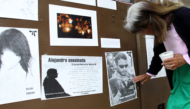 Una mujer coloca una veladora a la entrada del edificio donde fueron asesinadas cuatro mujeres y un fotoperiodista. Foto/EFE