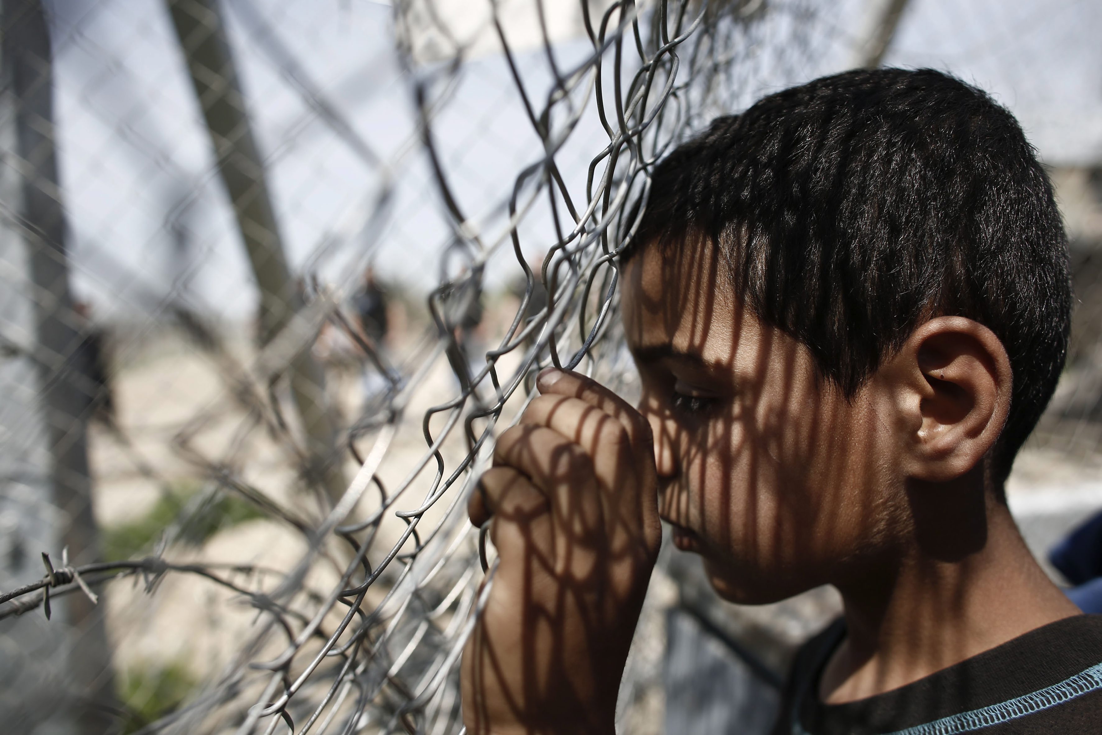 ATA02 IDOMENI (GRECIA), 07/04/2016.- Un niño se apoya en una valla durante una manifestación por la apertura de las fronteras a Macedonia en el campo improvisado de refugiados de Idomeni, Grecia hoy 7 de abril de 2016. Las llegadas de refugiados a las costas griegas desde Turquía se mantienen en niveles bajos, ya que en las últimas 24 horas han desembarcado 76 personas, la mayoría en la isla de Quíos. La tendencia se mantiene estable con respecto a las cifras de la víspera, cuando llegaron 68 refugiados a territorio griego. EFE/Kostas Tsironis