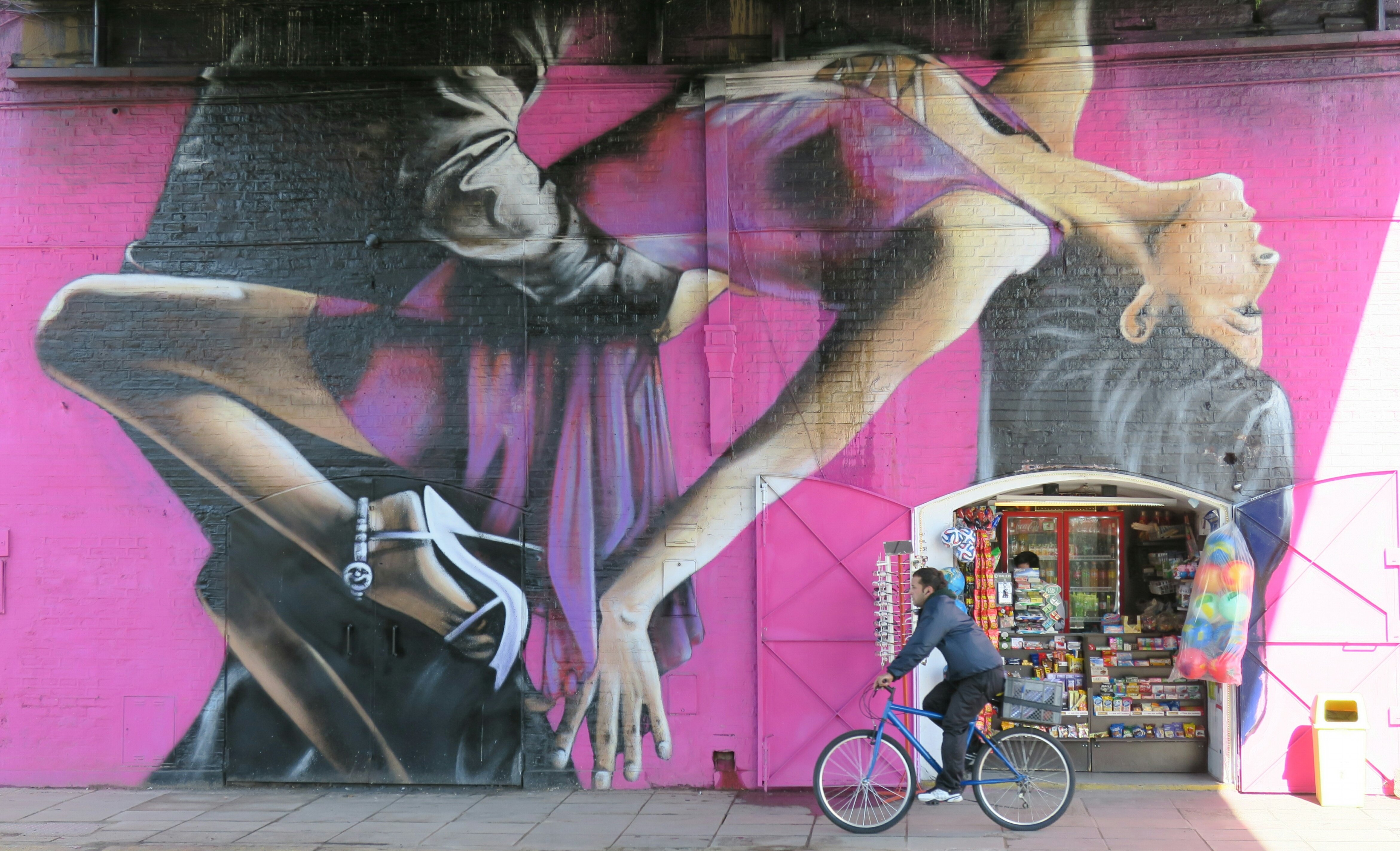 BAS01. BUENOS AIRES (ARGENTINA), 31/07/2016.- Fotografía del 28 de julio de 2016, de una persona pasando en bicicleta junto a un fragmento del mural pintado por el artista argentino Alfredo Segatori, en Buenos Aires (Argentina). El bandoneón, la tradicional milonga, Carlos Gardel, la pasión en el tango y su vínculo con las carreras de caballos componen un mural que ha trasladado el ritmo del 2x4 hasta las mismas paredes de Buenos Aires. Un homenaje producto de los aerosoles del artista argentino Alfredo Segatori. EFE/Irene Valiente