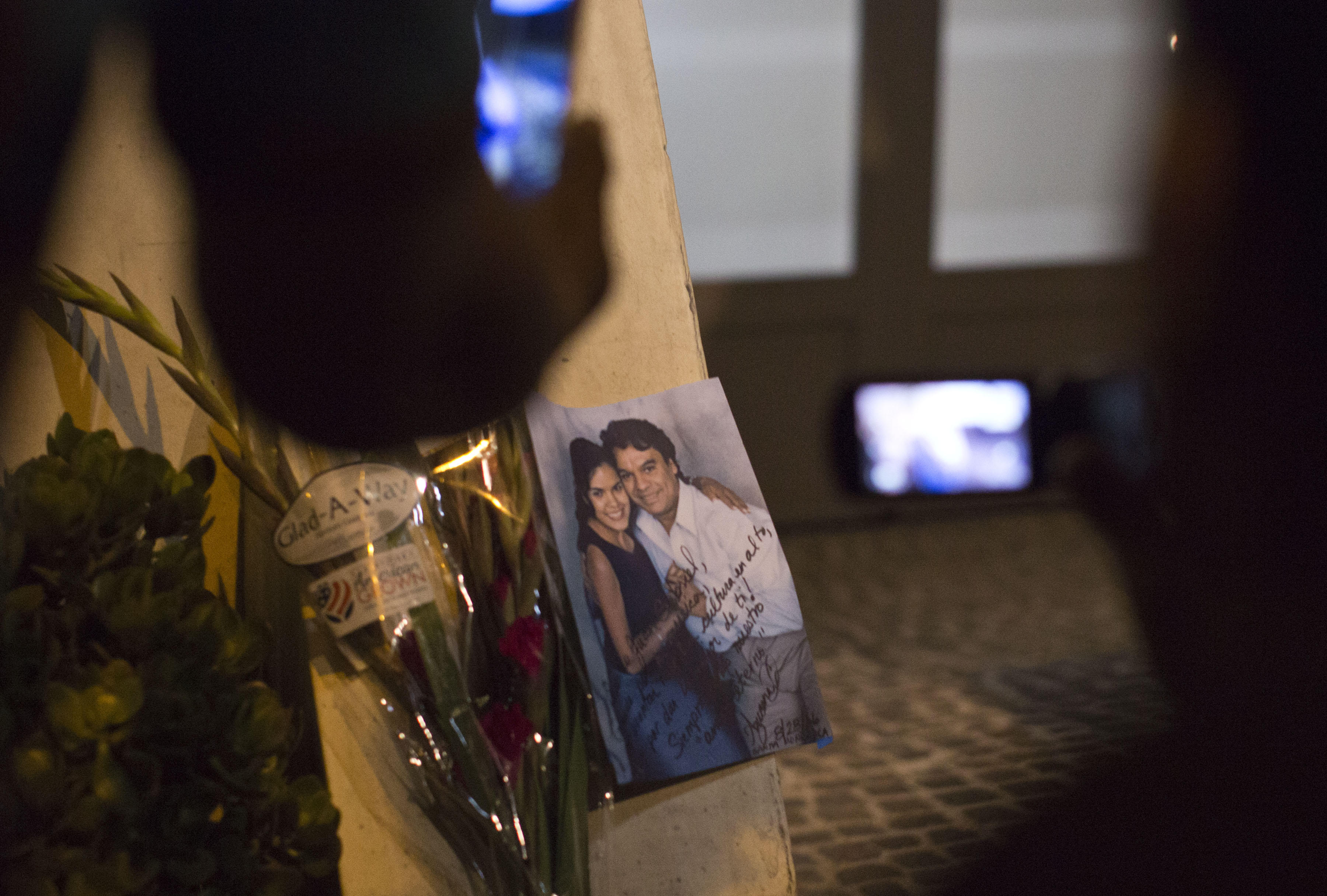 EUA01. HOLLYWOOD (EEUU), 28/08/2016.- Vista de una foto y algunas flores con que un grupo de personas rinden tributo al cantante Juan Gabriel, una de las estrellas musicales más importantes de México, en su casa ubicada en Santa Mónica, California (Estados Unidos). El presidente de México, Enrique Peña Nieto, y medios locales informaron hoy del fallecimiento del divo mexicano a los 66 años debido a un infarto al corazón, dos días después de dar su último concierto en el Fórum de Los Ángeles. EFE/RODOLFO DE LUNA