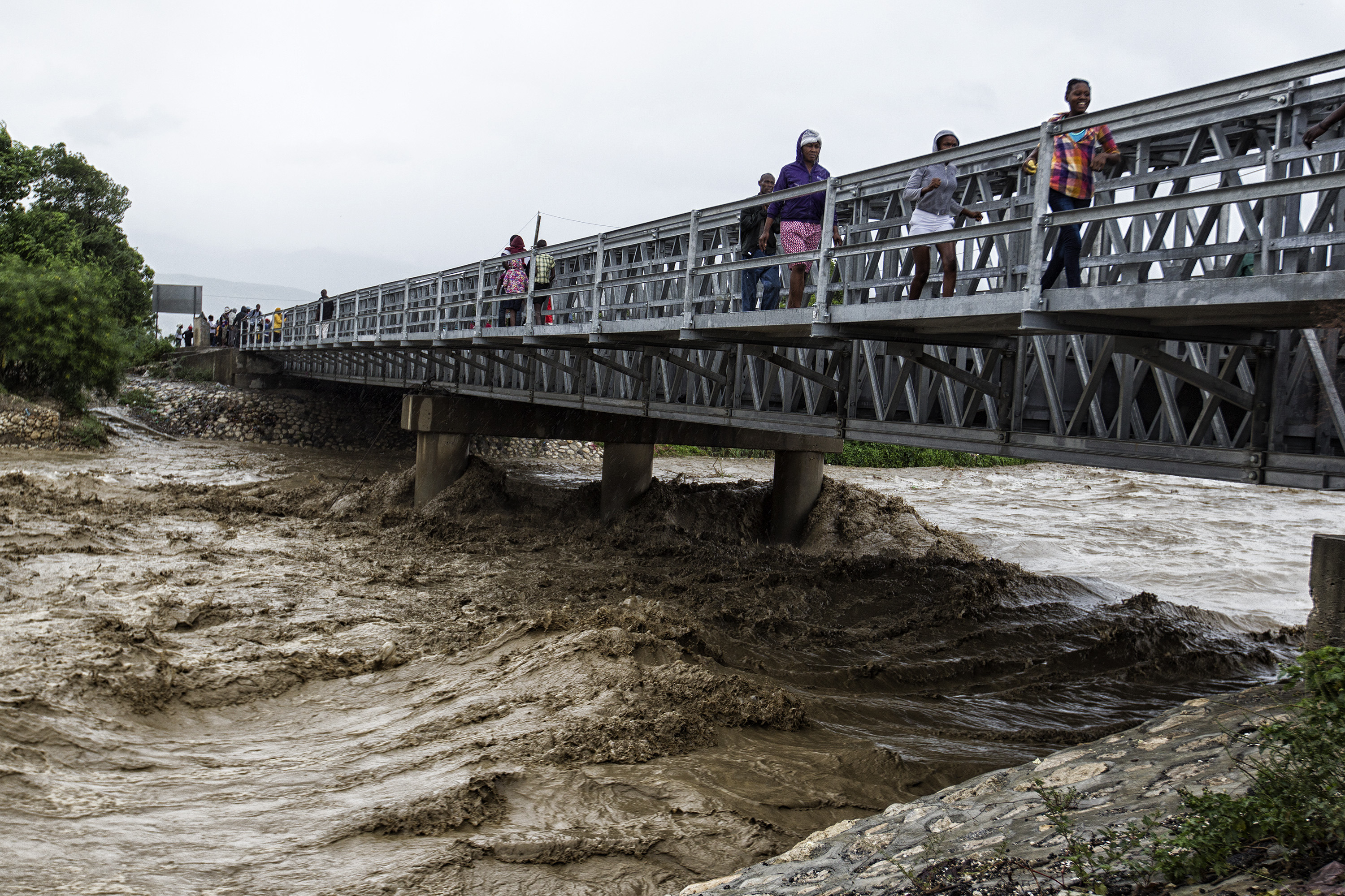 (161006) -- PUERTO PRINCIPE, octubre 6, 2016 (Xinhua) -- Imagen cedida por el Fondo de Naciones Unidas para la Infancia (UNICEF, por sus siglas en inglés) del 4 de octubre de 2016 de personas cruzando un puente sobre el río Grise, durante el primer día del paso del huracán "Matthew", en la cidad de Puerto Príncipe, capital de Haití. El huracán "Matthew" de categoría 4, afectó el martes Haití desplazándose con vientos de hasta 320km por hora, destruyendo viviendas y caminos y arrancando árboles. El huracán "Matthew" ha dejado al menos 108 muertos en Haití, informó el jueves el ministro haitiano de Interior, Francois Anick Joseph. (Xinhua/UNICEF) (jg) (ce) ***CREDITO OBLIGATORIO*** ***NO ARCHIVO-NO VENTAS*** ***SOLO USO EDITORIAL***