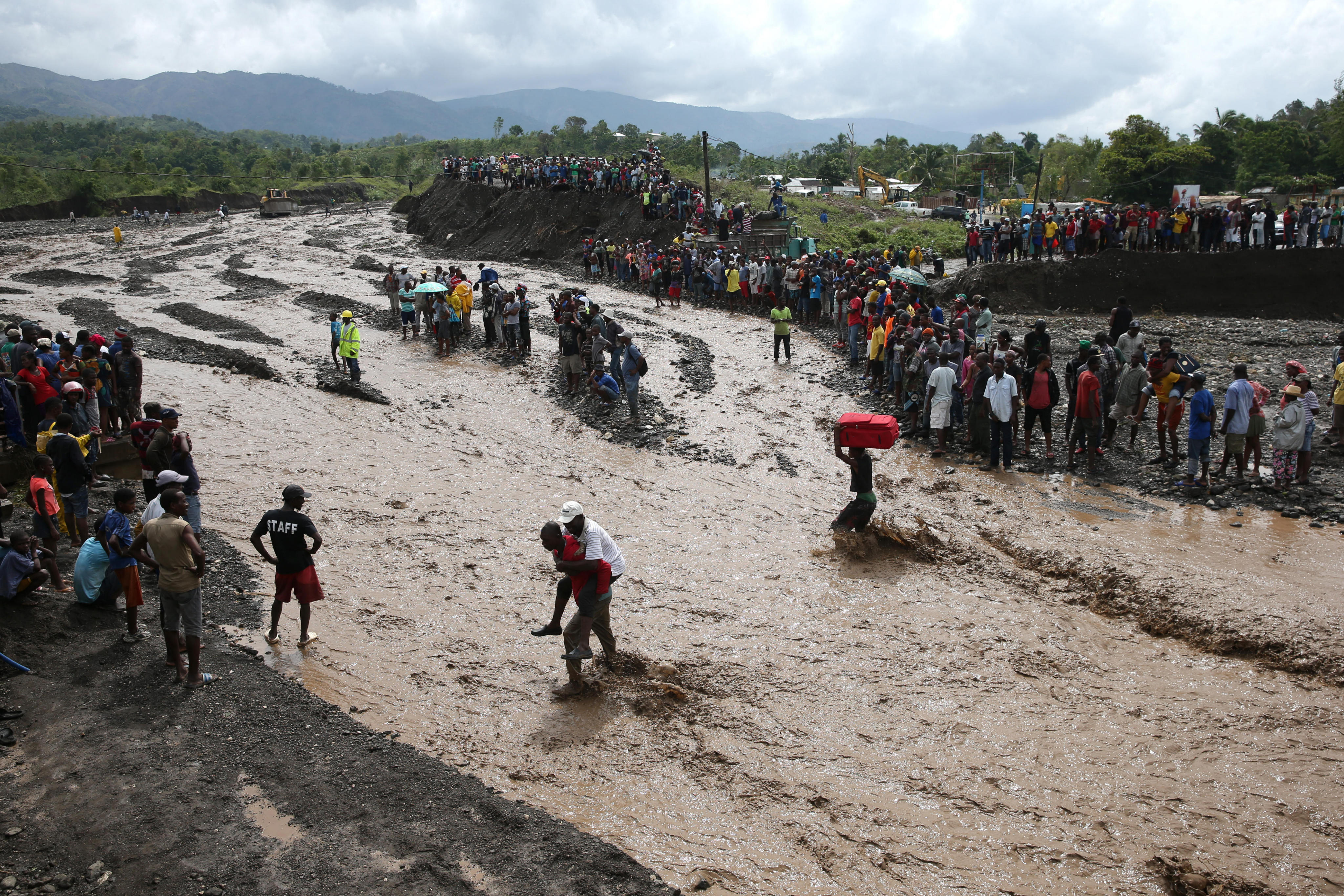 HAI01. PETIT GOAVE (HAITI), 05/10/16.- Personas intentan cruzar el río La Digue, debido al derrumbe del único puente que conecta con el sur, tras el paso del huracán Matthew hoy, 5 de octubre de 2016, en Petit Goave (Haití). El impacto del huracán Matthew en Haití, donde dejó al menos nueve muertos, miles de desplazados y comunidades incomunicadas, principalmente en el suroeste, obligó hoy a las autoridades electorales a aplazar los comicios del domingo. EFE/Orlando Barría