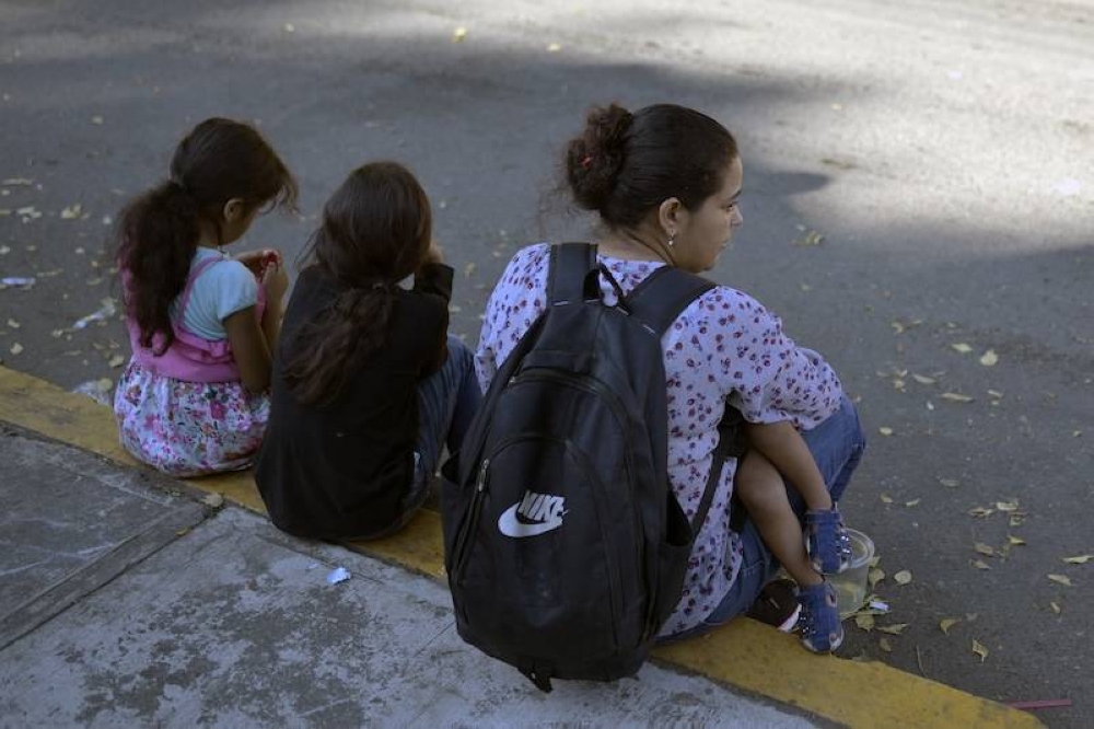 Una mujer migrante venezolana con tres hijos espera afuera de la oficina regional del Instituto Nacional de Migración para esperar su salvoconducto para transitar por territorio mexicano en su camino a Estados Unidos, en Tapachula, estado de Chiapas, México. / AFP