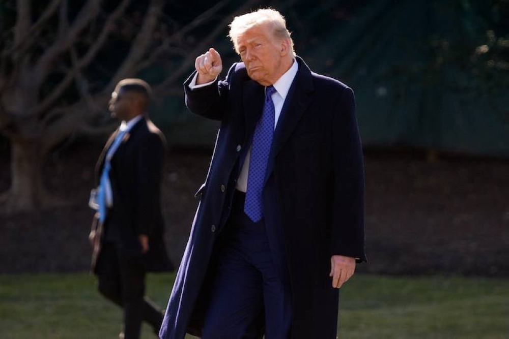 El presidente de Estados Unidos, Donald Trump, levanta el puño al descender del Air Force One a su llegada al Aeropuerto Internacional de Palm Beach, en West Palm Beach, Florida, el 14 de febrero de 2025, rumbo a su resort Mar-a-Lago./ AFP