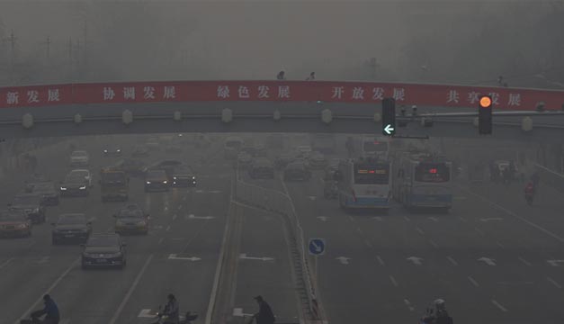 Coches circulan por una de las principales avenidas de Pekín en medio de una fuerte niebla causada por la contaminación. EFE