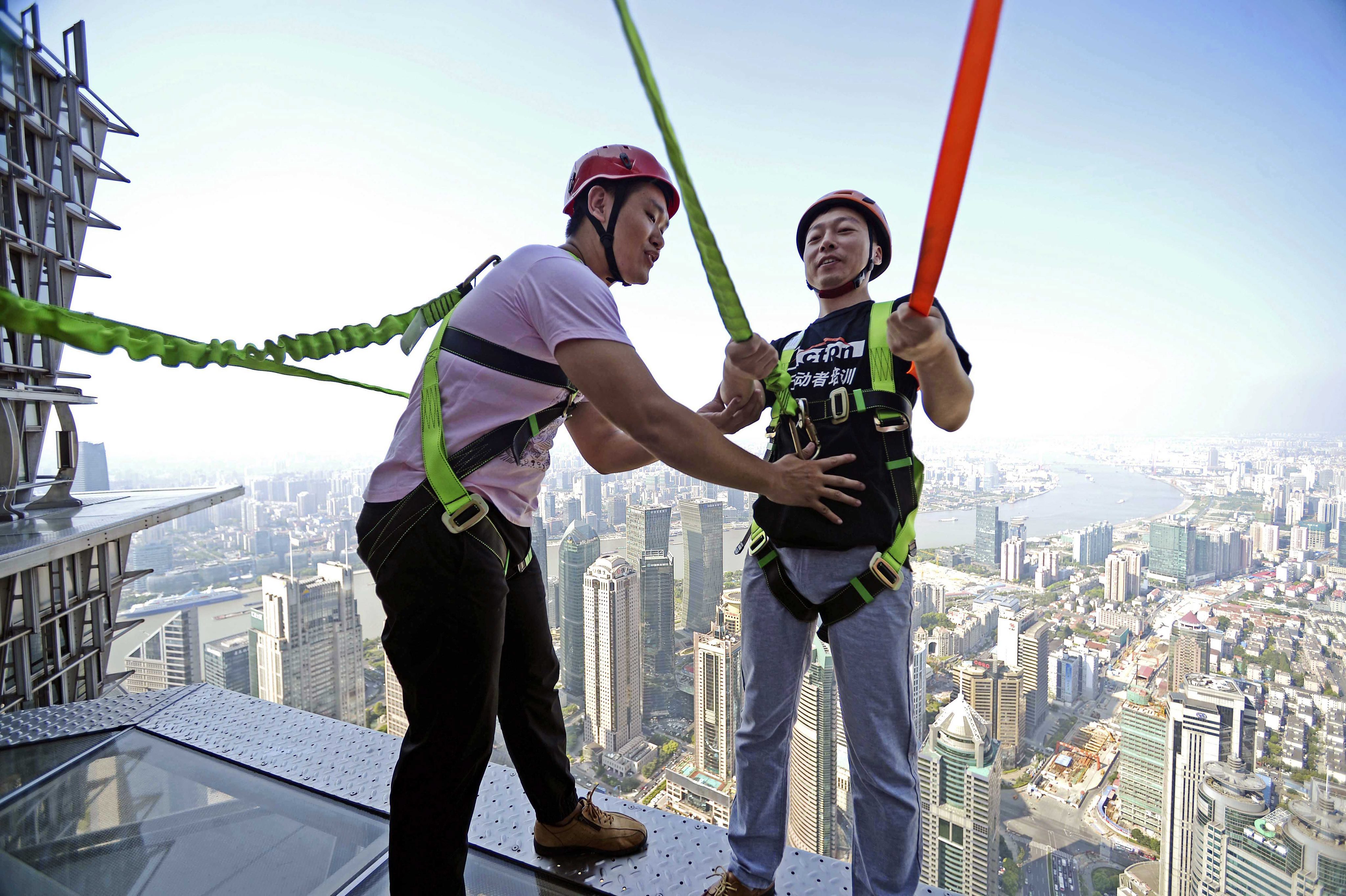 CH01. SHANGHÁI (CHINA), 28/07/2016.- Fotografía disponible hoy, viernes 29 de julio de 2016, de personas caminando sobre una pasarela acristalada en el piso 88 de la Torre Jinmao en Shanghái (China). La pasarela está abierta a los turistas, quienes pueden caminar ayudados de cuerdas de seguridad. EFE/XI LI/PROHIBIDO SU USO EN CHINA