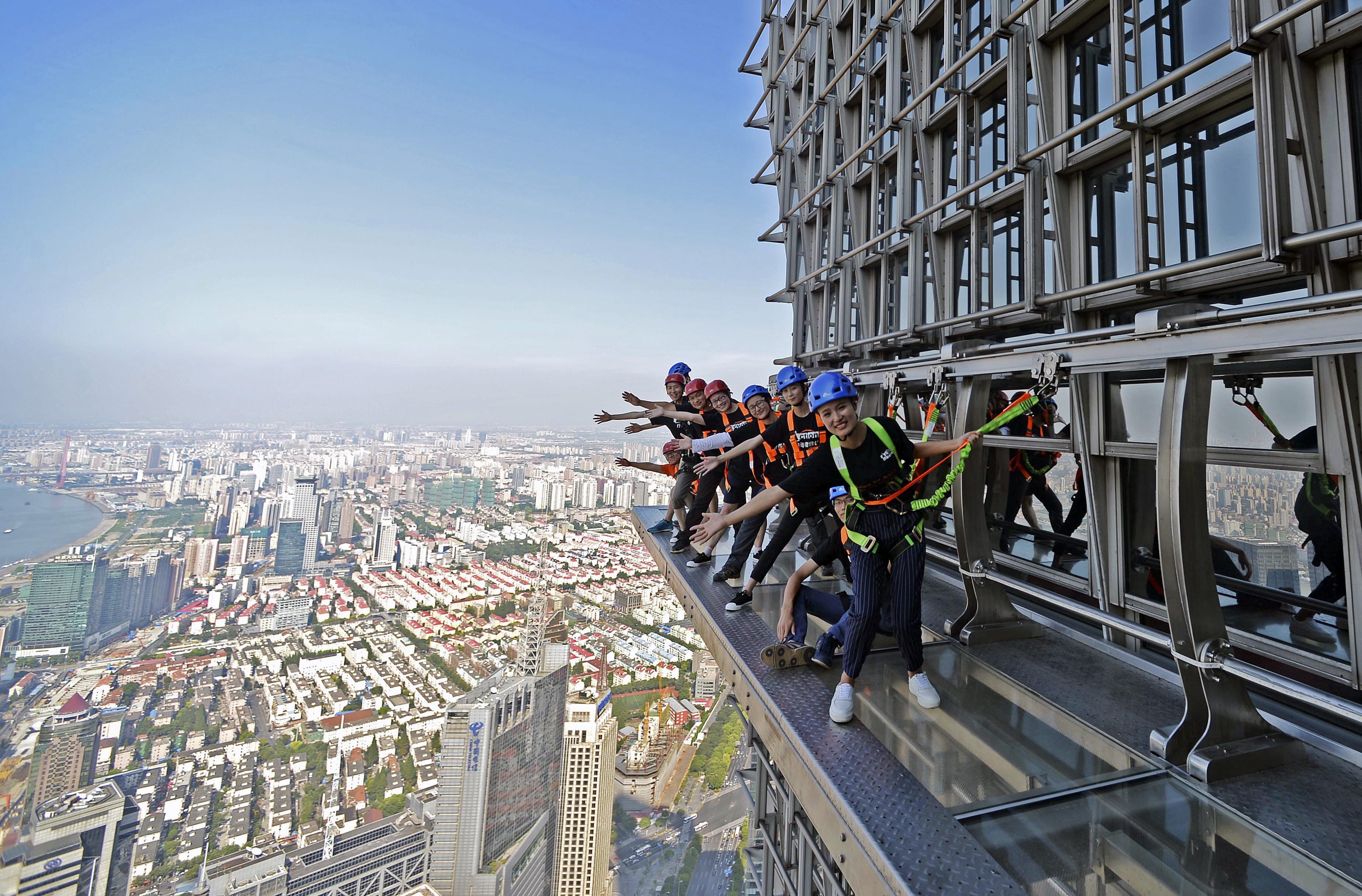 CH01. SHANGHÁI (CHINA), 28/07/2016.- Fotografía disponible hoy, viernes 29 de julio de 2016, de personas caminando sobre una pasarela acristalada en el piso 88 de la Torre Jinmao en Shanghái (China). La pasarela está abierta a los turistas, quienes pueden caminar ayudados de cuerdas de seguridad. EFE/XI LI/PROHIBIDO SU USO EN CHINA